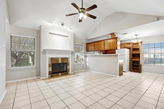 kitchen featuring ceiling fan, white fridge, light tile patterned floors, and a tiled fireplace