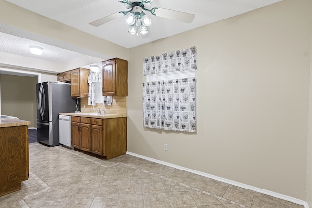 kitchen with decorative backsplash, a textured ceiling, sink, dishwasher, and stainless steel fridge with ice dispenser