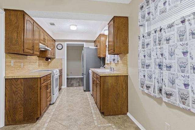 kitchen featuring sink, decorative backsplash, light tile patterned floors, a textured ceiling, and white range with electric stovetop