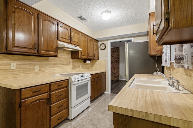 kitchen featuring a textured ceiling, white electric range oven, sink, and tasteful backsplash