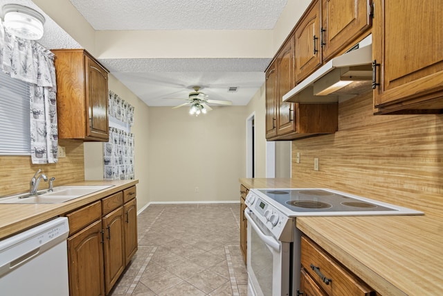 kitchen featuring white appliances, backsplash, sink, ceiling fan, and a textured ceiling