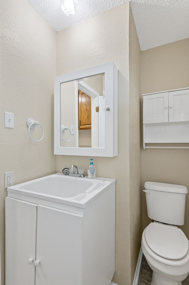 bathroom with vanity, a textured ceiling, and toilet