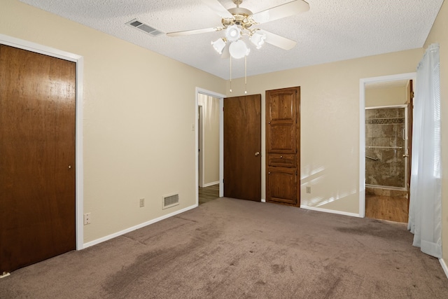 unfurnished bedroom with carpet, ceiling fan, a textured ceiling, and ensuite bath