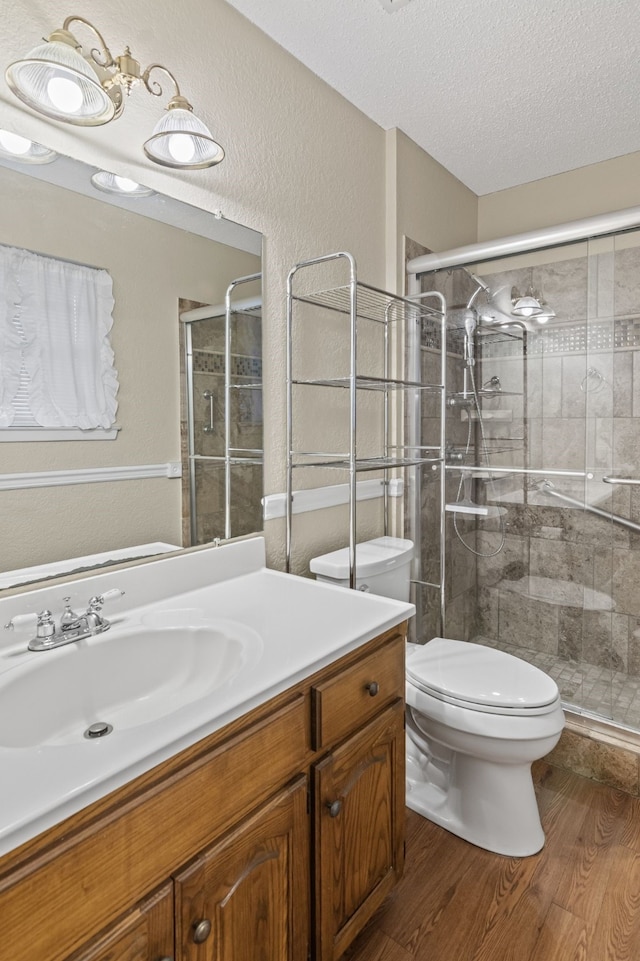 bathroom with vanity, hardwood / wood-style flooring, toilet, a textured ceiling, and an enclosed shower