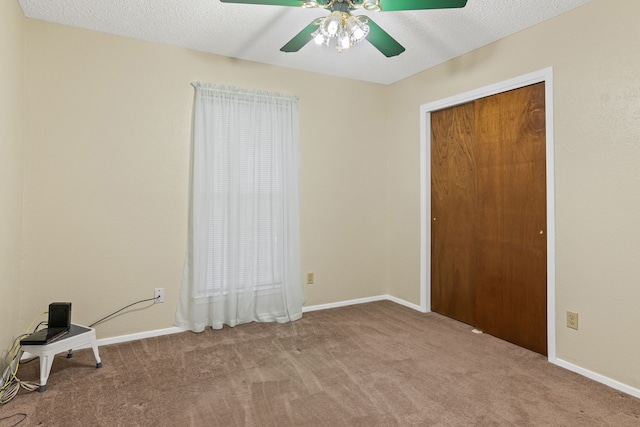 interior space with a textured ceiling, ceiling fan, light carpet, and a closet