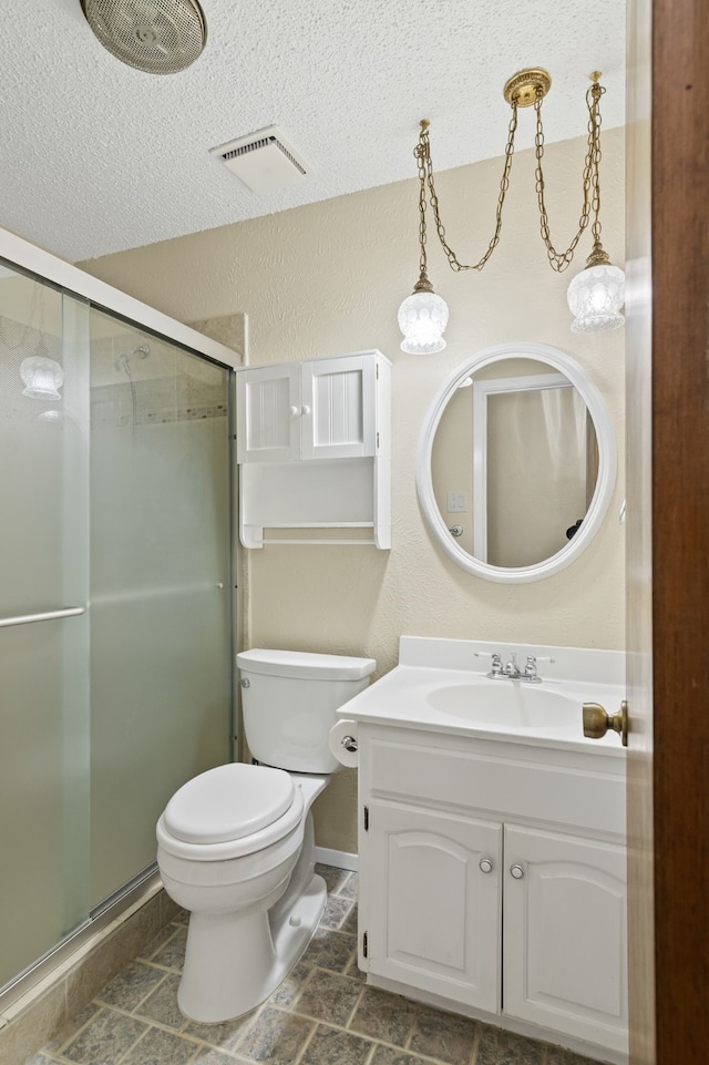 bathroom featuring vanity, toilet, a shower with door, and a textured ceiling