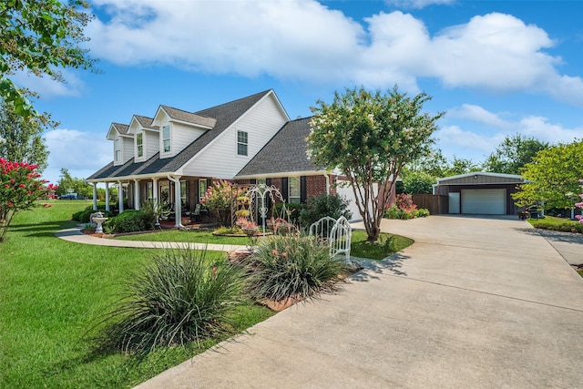 cape cod home with covered porch, a garage, a front lawn, and an outdoor structure