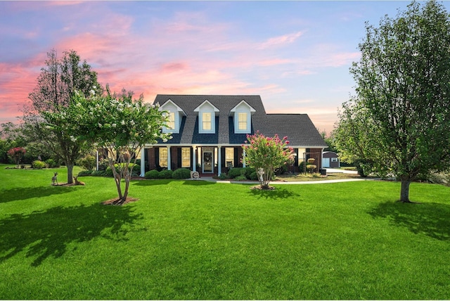 cape cod house featuring a yard