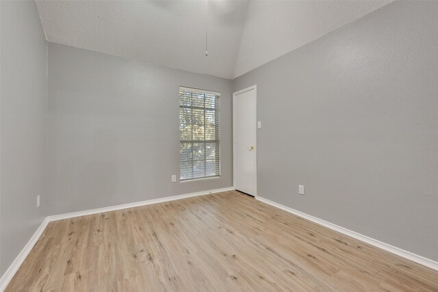 unfurnished room with light wood-type flooring and vaulted ceiling