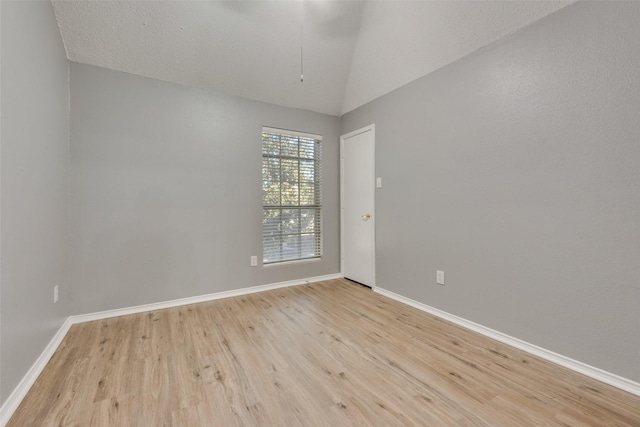 empty room with vaulted ceiling and light hardwood / wood-style flooring