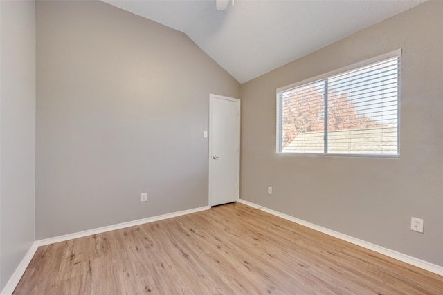 spare room with lofted ceiling and light wood-type flooring