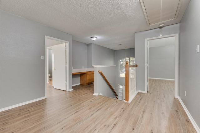 spare room with a textured ceiling and light hardwood / wood-style flooring