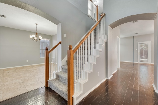 stairway with hardwood / wood-style floors and a chandelier