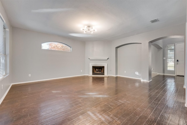 unfurnished living room with a textured ceiling and dark hardwood / wood-style flooring