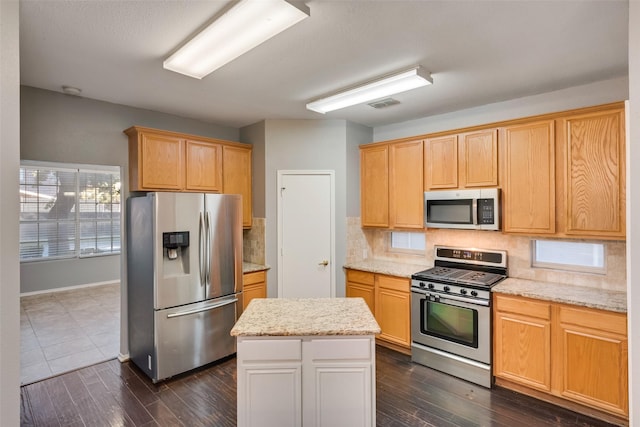 kitchen featuring a center island, decorative backsplash, light stone countertops, appliances with stainless steel finishes, and dark hardwood / wood-style flooring