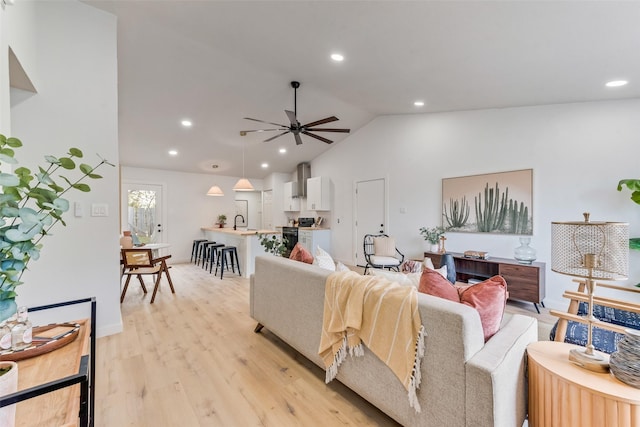 living room featuring vaulted ceiling, light hardwood / wood-style flooring, ceiling fan, and sink