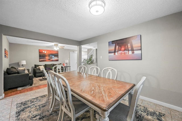 tiled dining space with ceiling fan and a textured ceiling