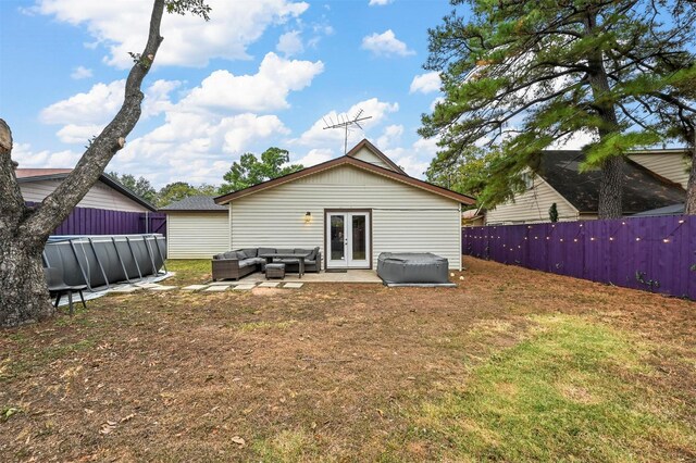 rear view of house with outdoor lounge area, a yard, a swimming pool, and french doors