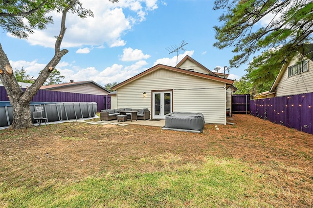 rear view of property with a patio area, a yard, french doors, an outdoor living space, and a pool