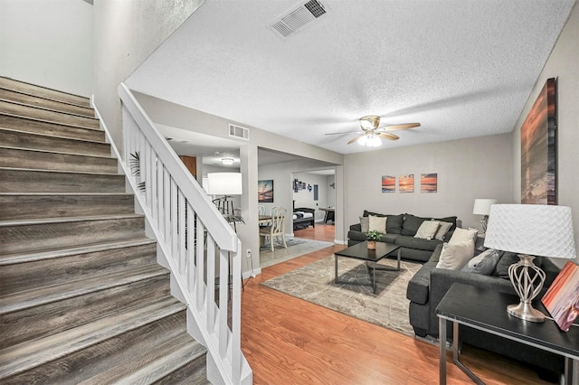 living room featuring ceiling fan, hardwood / wood-style floors, and a textured ceiling