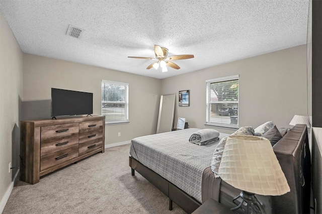 bedroom with ceiling fan, a textured ceiling, and light carpet