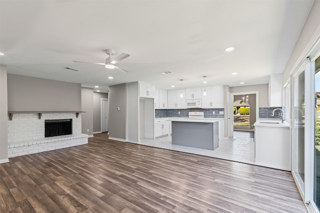 unfurnished living room with a fireplace, wood-type flooring, ceiling fan, and sink