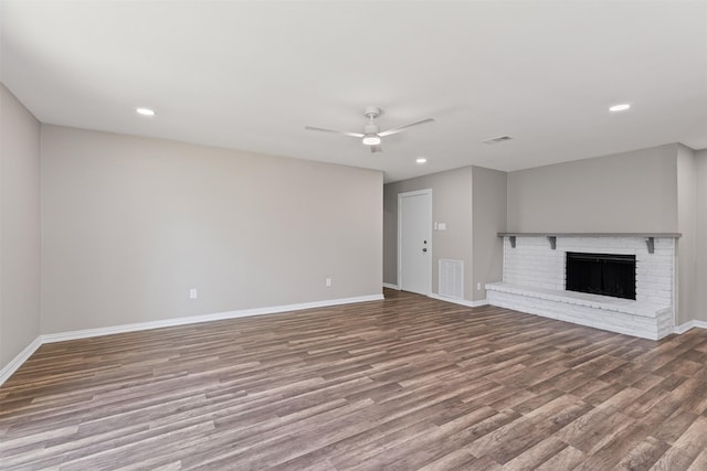 unfurnished living room featuring ceiling fan, wood-type flooring, and a brick fireplace