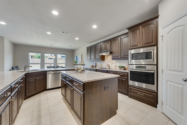 kitchen with dark brown cabinetry, stainless steel appliances, decorative light fixtures, and sink