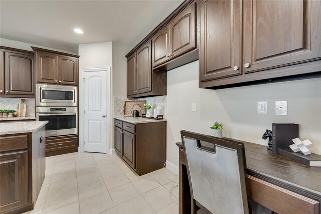 kitchen featuring tasteful backsplash, dark brown cabinetry, light tile patterned flooring, and stainless steel appliances