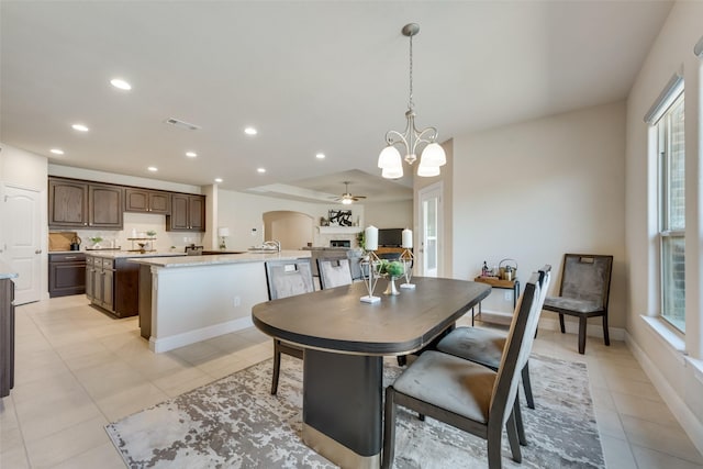 tiled dining space featuring plenty of natural light and ceiling fan with notable chandelier