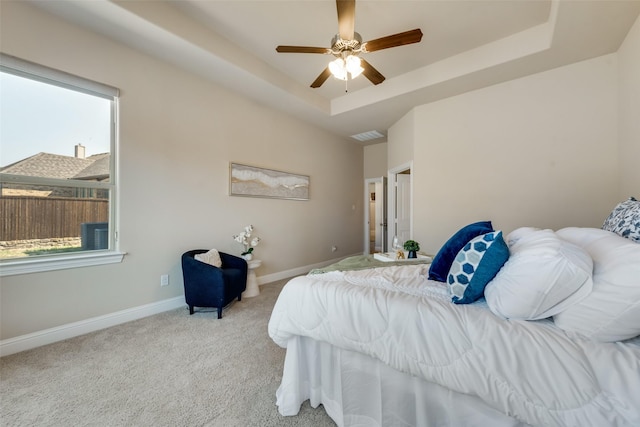 carpeted bedroom featuring a tray ceiling and ceiling fan