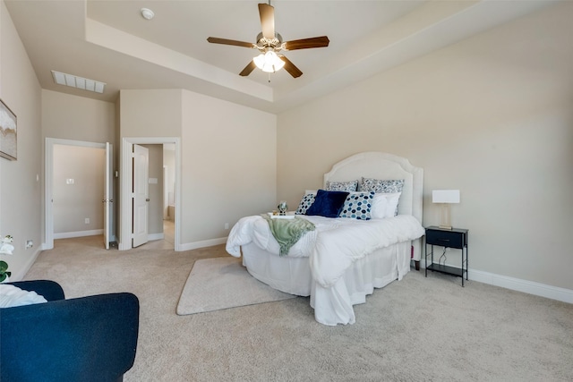 carpeted bedroom with ceiling fan and a tray ceiling