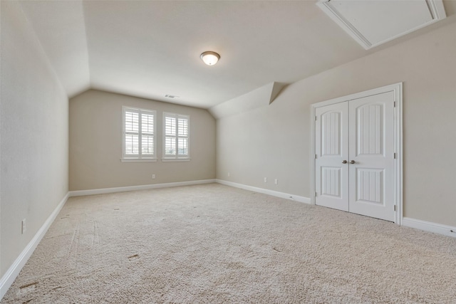 additional living space featuring light colored carpet and vaulted ceiling