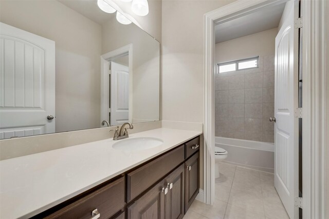 full bathroom with tiled shower / bath, tile patterned flooring, vanity, and toilet