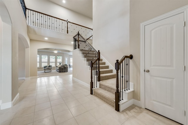 tiled entryway with ceiling fan and a high ceiling