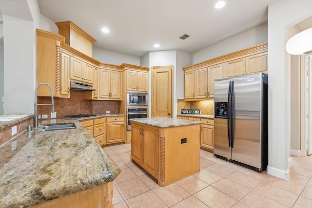 kitchen featuring a kitchen island, light stone countertops, light brown cabinets, and appliances with stainless steel finishes