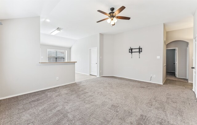 spare room featuring light carpet, vaulted ceiling, and ceiling fan