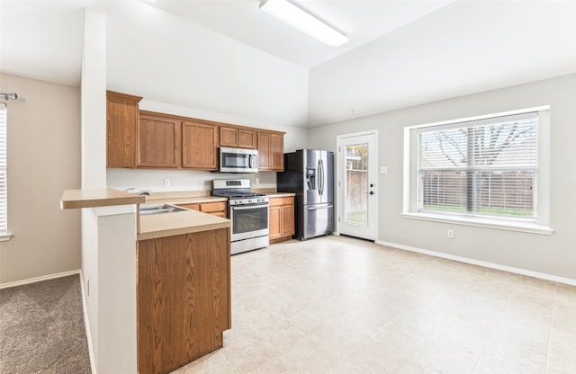 kitchen featuring kitchen peninsula, appliances with stainless steel finishes, lofted ceiling, and sink