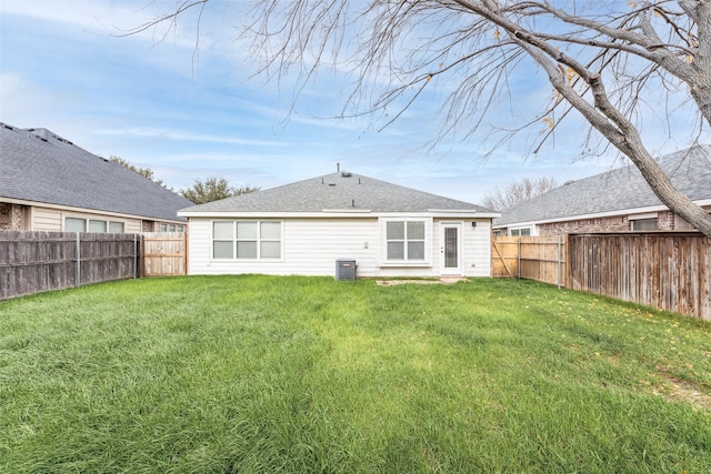 rear view of property featuring central AC and a lawn