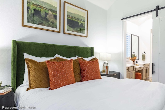 bedroom featuring vaulted ceiling, a barn door, and ensuite bathroom