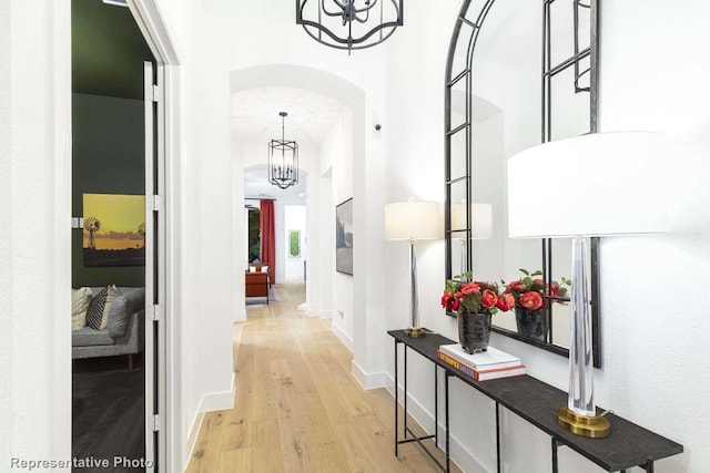 hallway with light hardwood / wood-style floors and a notable chandelier