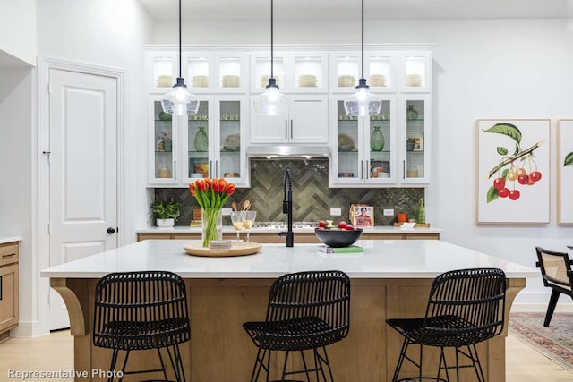 bar featuring decorative backsplash, light hardwood / wood-style flooring, white cabinets, and decorative light fixtures