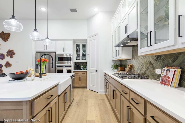 kitchen with white cabinetry, tasteful backsplash, hanging light fixtures, a center island with sink, and stainless steel appliances