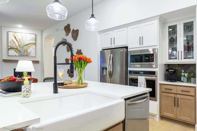 kitchen with decorative light fixtures, white cabinetry, sink, decorative backsplash, and stainless steel appliances