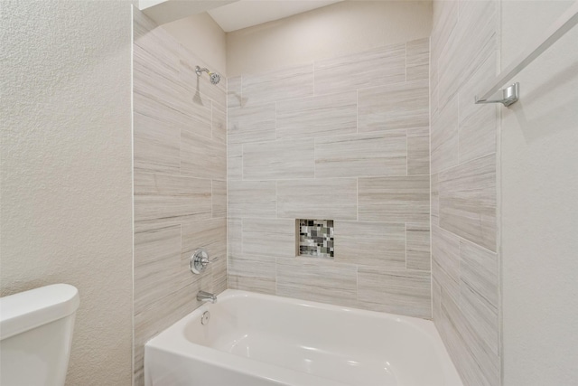 bathroom with tiled shower / bath combo and toilet