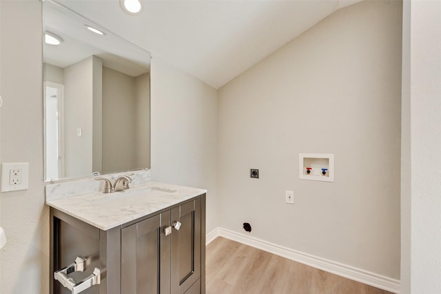 washroom featuring electric dryer hookup, sink, washer hookup, and light hardwood / wood-style flooring