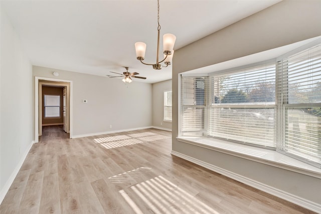 spare room with ceiling fan with notable chandelier and light hardwood / wood-style flooring