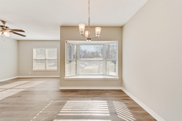 interior space with ceiling fan with notable chandelier, a healthy amount of sunlight, and wood-type flooring