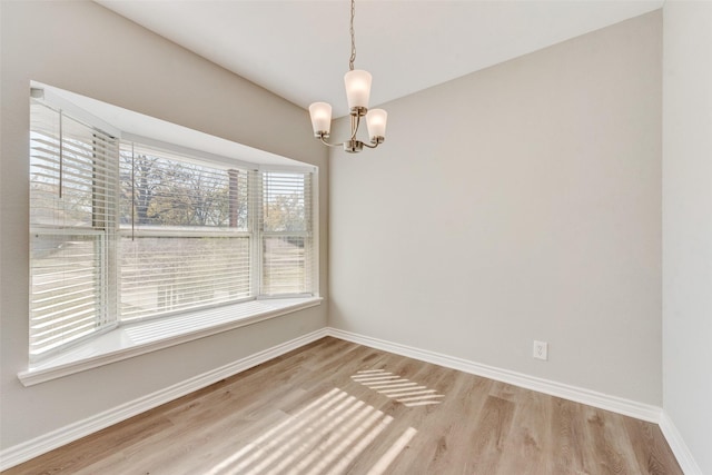 spare room featuring wood-type flooring and a notable chandelier