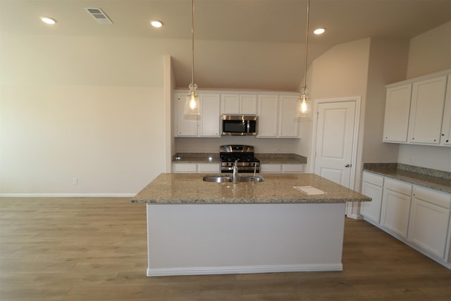 kitchen featuring hanging light fixtures, white cabinetry, a center island with sink, and appliances with stainless steel finishes